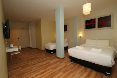 a hotel room with two beds and a desk and a television at Ipoh Boutique Hotel in Ipoh
