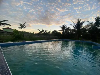 a large swimming pool with a cloudy sky above it at AsiaCamp - Chalet Sungai Sireh in Tanjung Karang