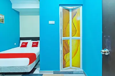 a blue room with a bed and a glass door at Hotel O Bamboo Inn in Batu Ferringhi