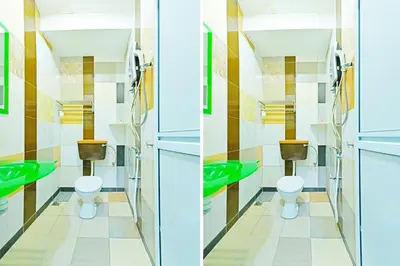 a bathroom with two toilets and green sinks at Hotel O Bamboo Inn in Batu Ferringhi