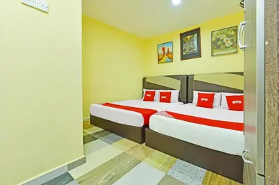 a bedroom with two beds with red pillows at Hotel O Bamboo Inn in Batu Ferringhi