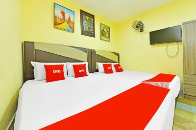 a bedroom with a large bed with red pillows at Hotel O Bamboo Inn in Batu Ferringhi