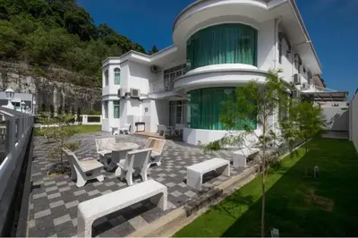 a large white house with a patio with chairs at 6, Persiaran Tanjung Bunga 3 in Batu Ferringhi