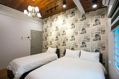two beds in a bedroom with a wall covered in newspaper at Canning 33 in Ipoh