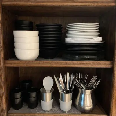 a shelf with plates and bowls and utensils at G Beach Front Villa in Batu Ferringhi