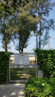 a gate with a sign in front of some trees at By The Sea Beach Luxury Resort - Batu Ferringhi in Batu Ferringhi