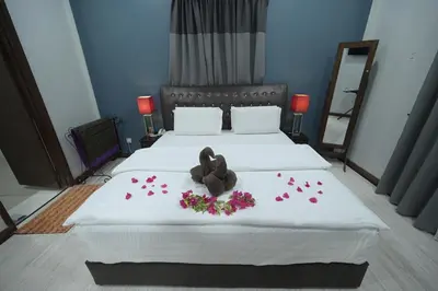a bedroom with two beds with flowers and a teddy bear on it at Hotel Denai in Gua Musang