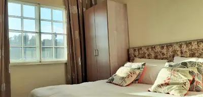 a bedroom with a bed with pillows and a window at Teaz Apartment @ Iris House Resort in Cameron Highlands