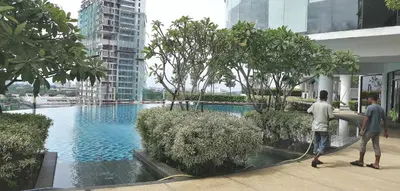 two men are standing next to a pool in a building at Mevin Woodsbury Suite Butterworth Penang in Butterworth