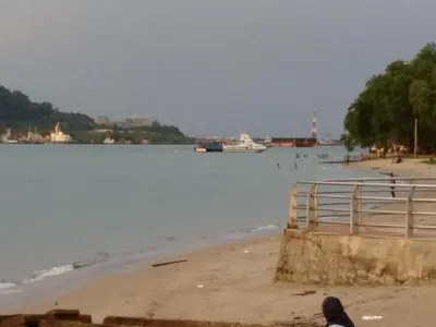a person sitting on a beach near the water at Desair Apartment By SCHT in Lumut