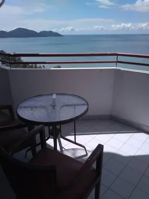 a table on a balcony with a view of the ocean at The Barn private home @ Sri Sayang Apartment in Batu Ferringhi