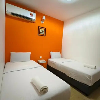 two beds in a room with an orange wall at Nice Inn in George Town