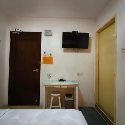 a room with a bed and a desk and a television at Nice Inn in George Town