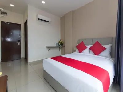 a bedroom with a large white bed with red pillows at Hotel Raub Agro in Raub