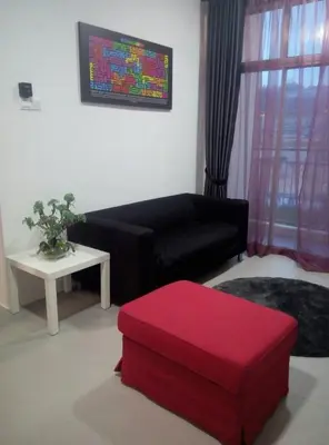 a living room with a black couch and a red stool at MUSLIM 2 BED ROOM APARTMENT GOLDEN HILL in Brinchang