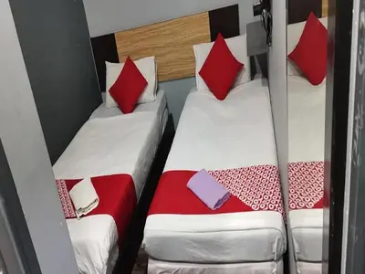 two beds in a small room with red and white pillows at Lucky Hotel in Sungai Petani