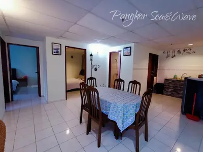 a dining room with a table and chairs and a bedroom at Sea & Wave #2 Coral Bay Apartment in Pangkor
