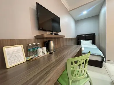 a room with a desk with a tv and a bed at Hilltop Hotel Tanjung Malim in Tanjung Malim