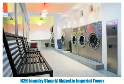 a laundry room with two washing machines and a bench at H2H - TT Court Majestic Ipoh in Ipoh