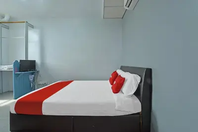 a bedroom with a bed with a red pillow on it at Hotel O Purple Town in Sekincan