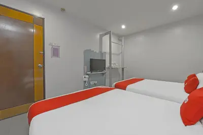 a bedroom with two white beds and a television at Hotel O Purple Town in Sekincan