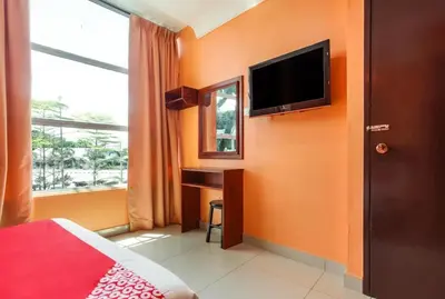 a bedroom with orange walls and a desk and a television at My Town Hotel in Ipoh