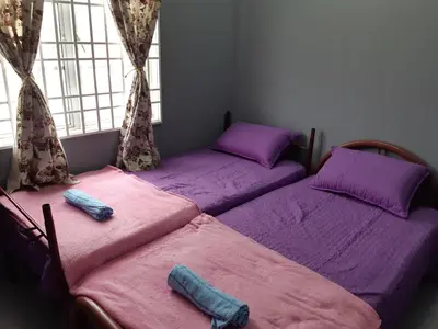 two twin beds in a room with purple sheets at Anis Homestay Gua Musang in Gua Musang