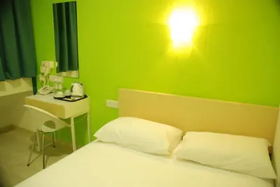 a bedroom with a green wall with a bed and a lamp at Old Penang Hotel - Penang Times Square in George Town
