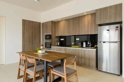 a kitchen with a wooden table and a refrigerator at By The Sea Beach Front Apartment in Batu Ferringhi