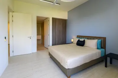 a bedroom with a bed and a door to a bathroom at By The Sea Beach Front Apartment in Batu Ferringhi