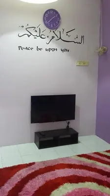 a living room with a television and a clock on the wall at Cottage Muslim Homestay ByWawaSha in Tanjung Malim
