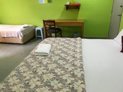 a room with two beds and a desk and a bed sidx sidx sidx at Hotel Cahaya in Tanjung Malim