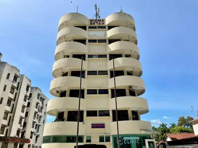 a tall white building with a sign on it at Hotel O Wg Guest House in George Town
