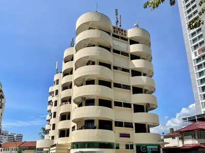 a tall white building with round windows at Hotel O Wg Guest House in George Town