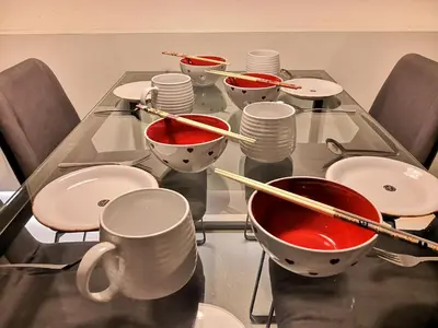 a glass table with bowls and chopsticks on it at Strait Garden Suites X Ace Pro @ George Town in Jelutong