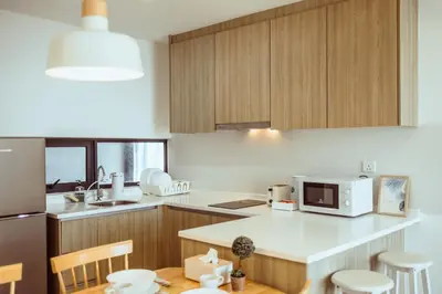 a kitchen with wooden cabinets and a white counter top at Muji X Tiffany - City and Hill View 3BR at 218 Tropicana NEAR Komtar Food Heaven with Netflix & TV Box in George Town