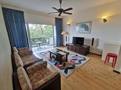 a living room with a couch and a tv and a table at Little England B8 in Bukit Fraser