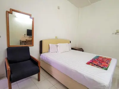 a bedroom with a bed and a mirror and a chair at Star Lodge in George Town
