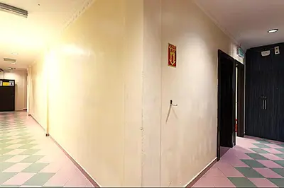 a hallway with a white wall and a black door at T P Hotel in Sitiawan