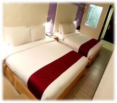 two beds sitting next to each other in a hotel room at Ritz Suites in Lumut