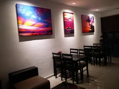 a restaurant with tables and chairs and paintings on the wall at Hotel Pangkor SJ in Pangkor