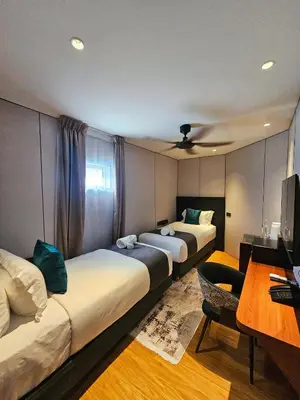 a room with two beds and a desk and a table at Carnarvon Suites in George Town
