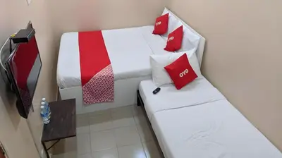 two beds in a small room with red pillows at Hotel O Hajah Rohayah in Tanjung Malim