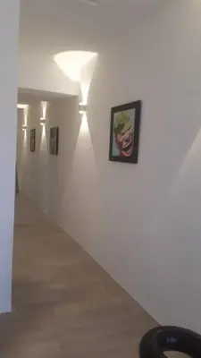a white hallway with pictures on the wall at COMFORTABLE STAY in Ayer Itam