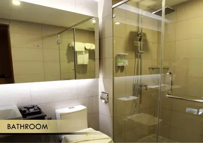 a bathroom with a shower and a toilet and a mirror at Symphony Suites Hotel in Ipoh