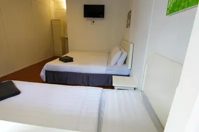 a small room with two beds and a tv at Vagary Pangkor in Pangkor
