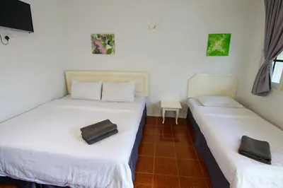two beds in a room with white sheets at Vagary Pangkor in Pangkor