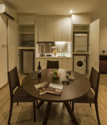 a dining room table with chairs and a kitchen at Luxfort 118 Service Suites in George Town