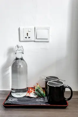 a plastic tray with a bottle of water and a cup at Earnest Hotel Georgetown in George Town