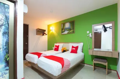 a bedroom with two beds and a green wall at Valley View Hotel in Lumut